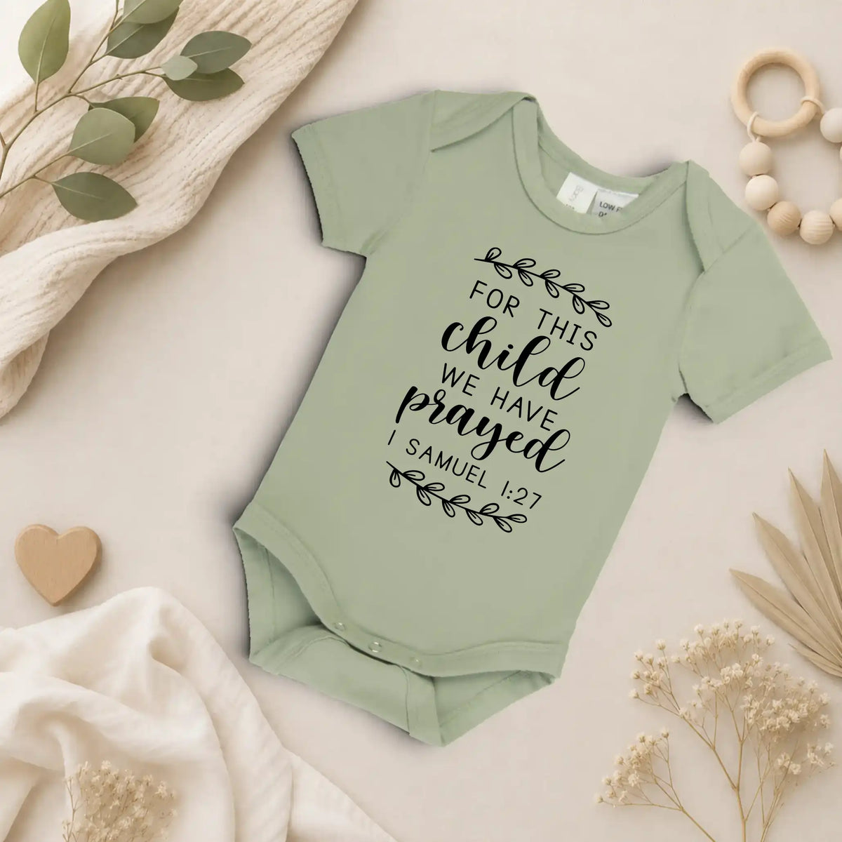 Eucalyptus coloured baby onesie with text on a neutral background