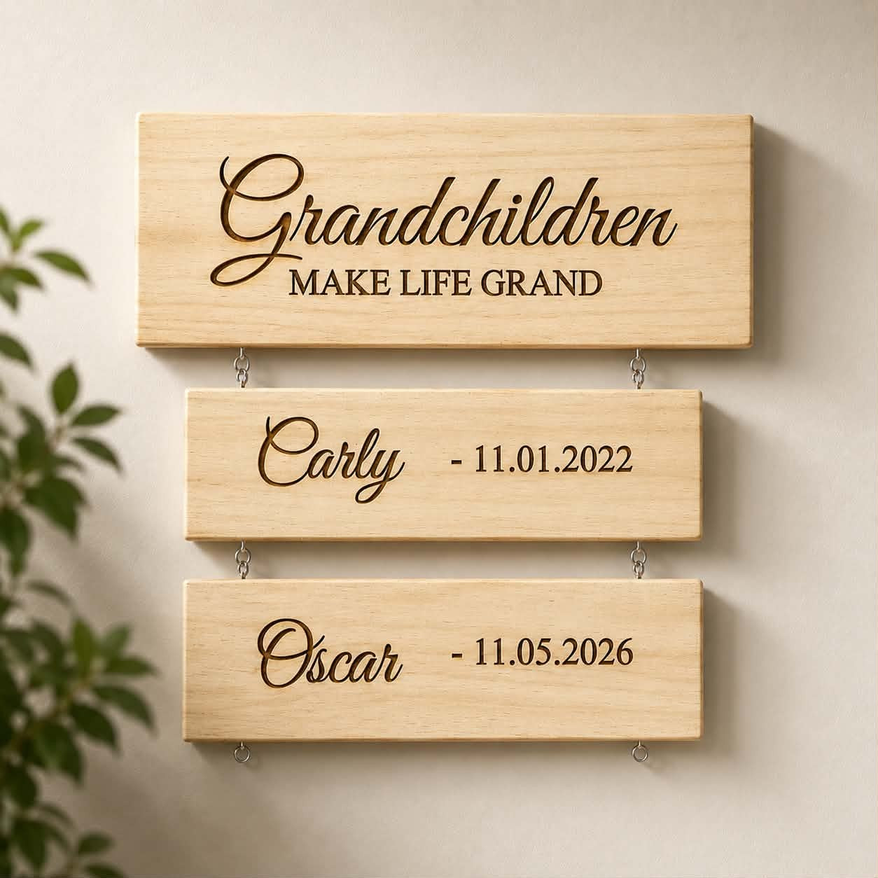 Personalised wooden 'Grandchildren Make Life Grand' hanging sign with engraved name plaques for Carly and Oscar, showing dates of birth, displayed on a wall"