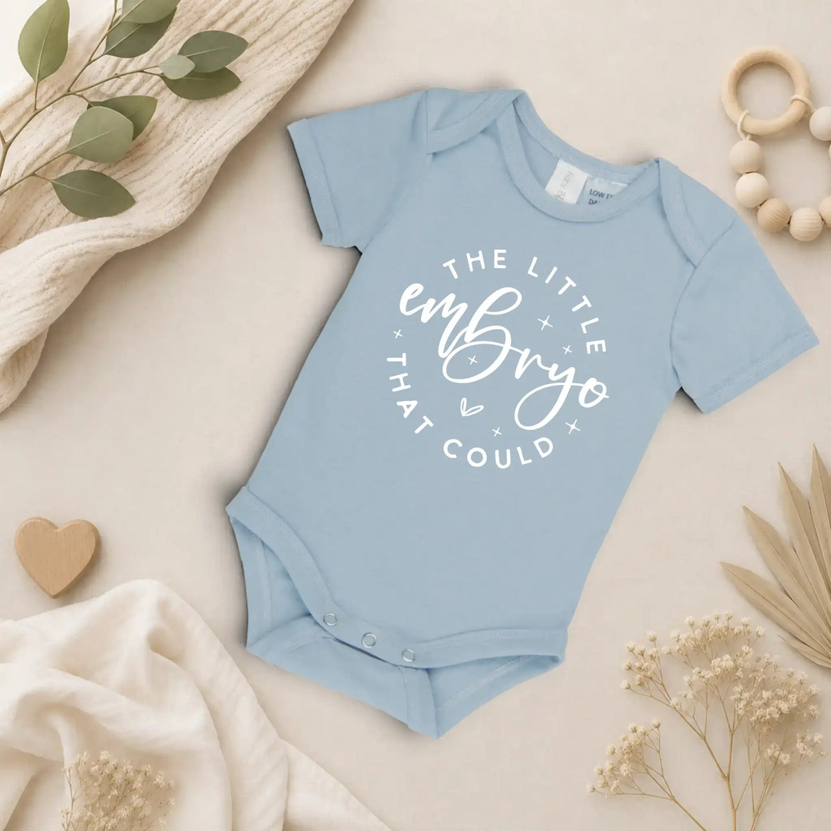 Ice blue baby onesie with text on a neutral background